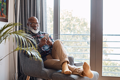 Buy stock photo Shot of a mature man using a cellphone while relaxing on a sofa at home