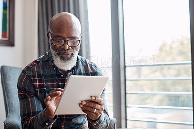 Buy stock photo Shot of a mature man using a digital tablet at home