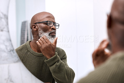 Buy stock photo Shot of a mature man examining his face in the bathroom at home
