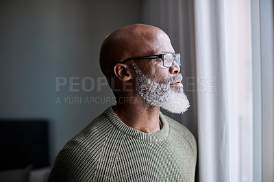 Buy stock photo Shot of a mature man looking thoughtfully through a window at home