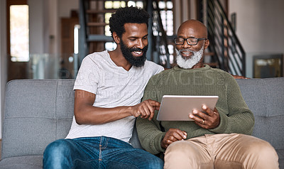 Buy stock photo Shot of a happy senior man using a digital tablet while spending some time with his adult son at home