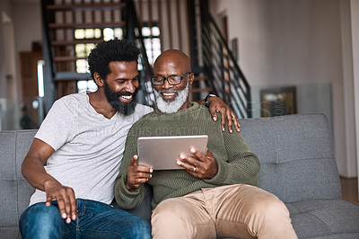 Buy stock photo Shot of a happy senior man using a digital tablet while spending some time with his adult son at home