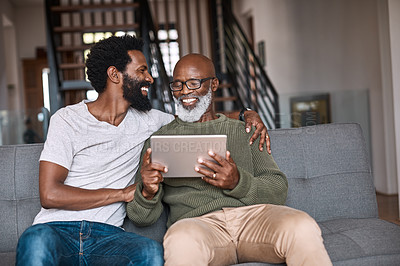 Buy stock photo Shot of a happy senior man using a digital tablet while spending some time with his adult son at home