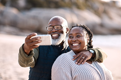 Buy stock photo Shot of a happy mature couple taking selfies with a smartphone at the beach