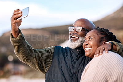 Buy stock photo Shot of a happy mature couple taking selfies with a smartphone at the beach