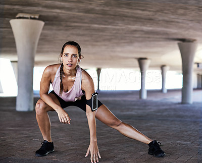 Buy stock photo Full length shot of an attractive young female athlete stretching during her workout in the city