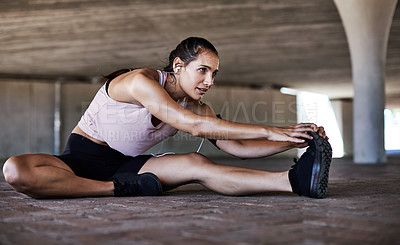 Buy stock photo Full length shot of an attractive young female athlete stretching during her workout in the city
