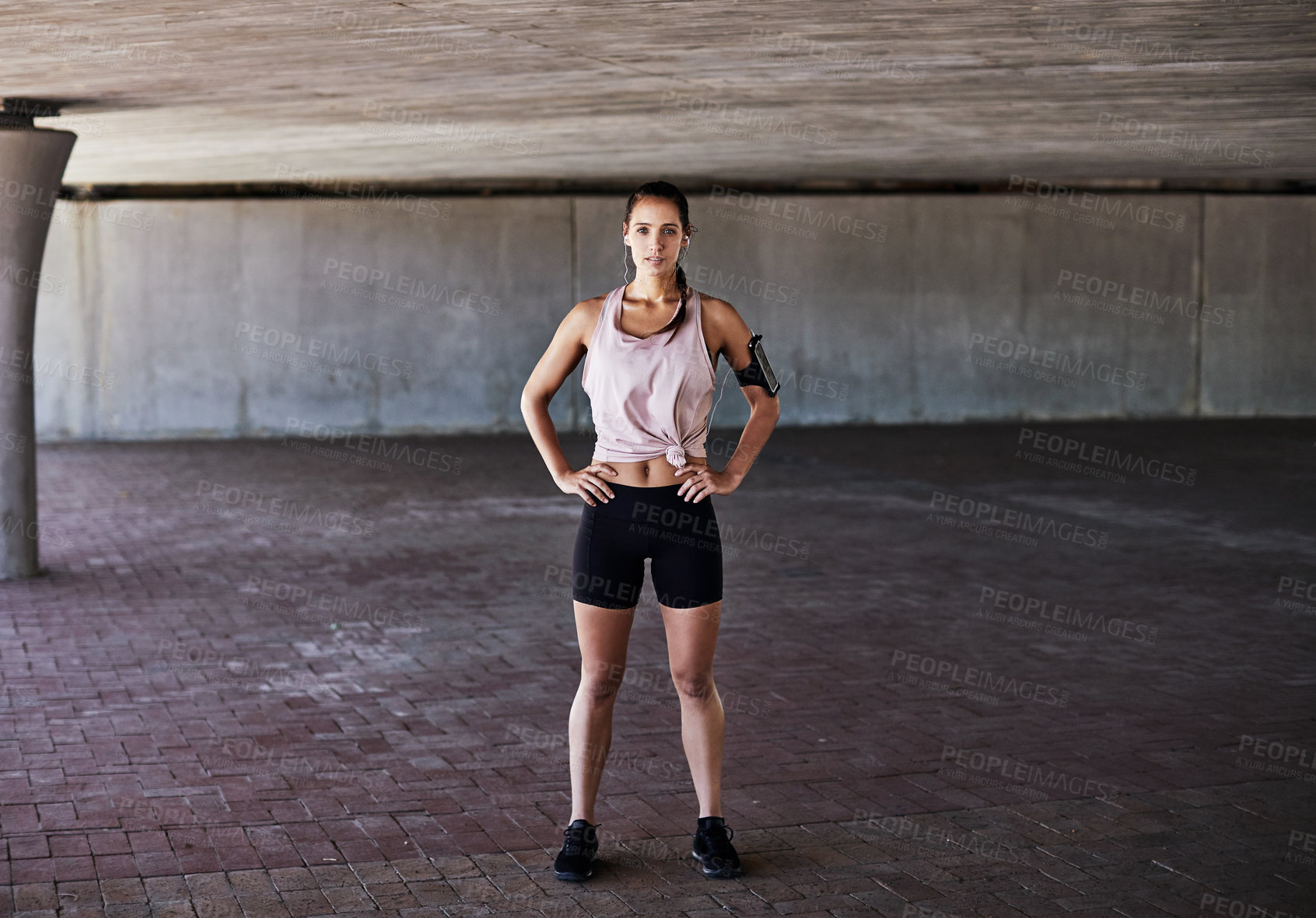 Buy stock photo Full length portrait of an attractive young female athlete standing with her hands on her hips while working out in the city