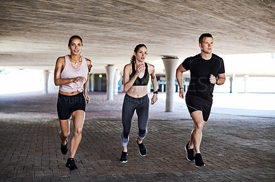 Buy stock photo Full length shot of three young athletes working out in the city