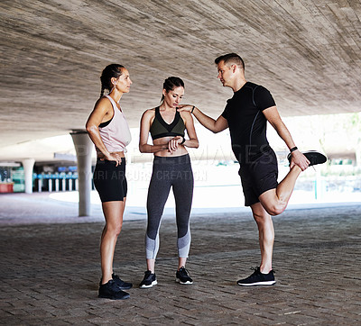 Buy stock photo Full length shot of three young athletes talking and checking their times while working out in the city