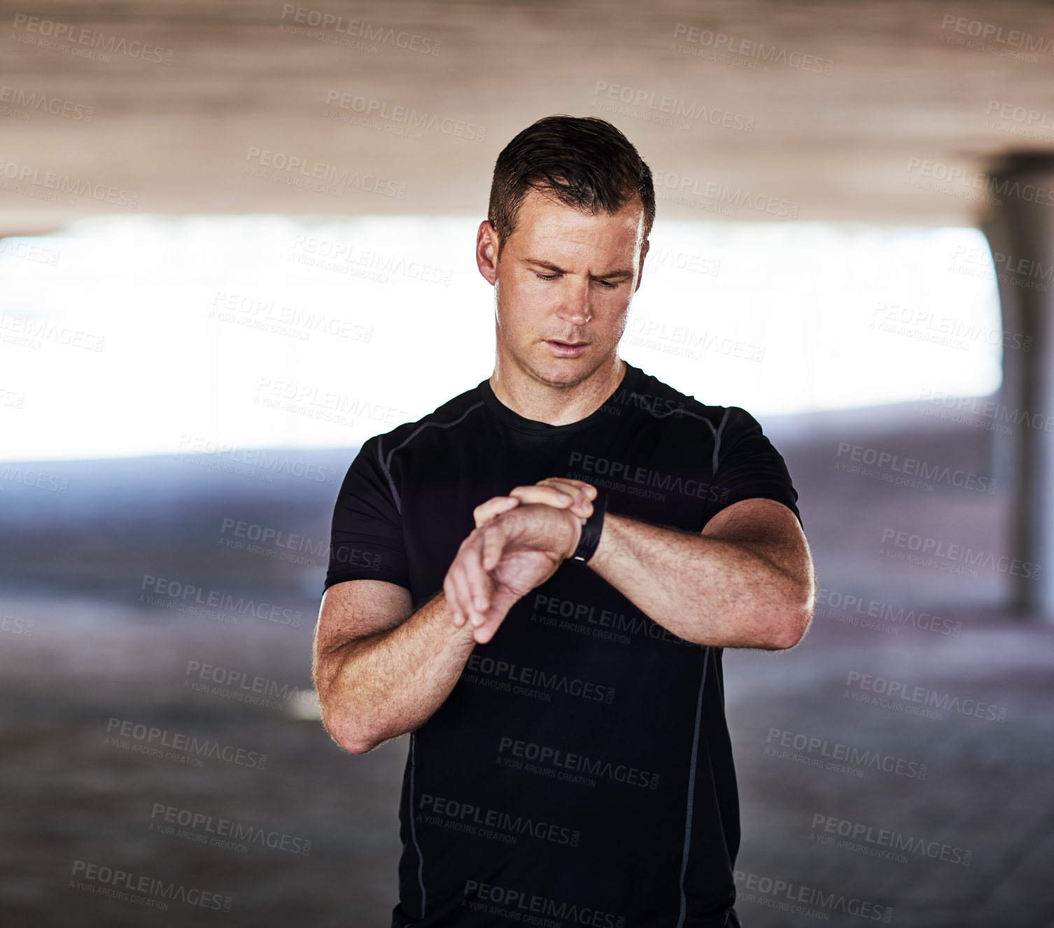 Buy stock photo Cropped shot of a handsome young male athlete checking his watch while working out in the city