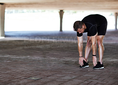 Buy stock photo Full length shot of a handsome young male athlete stretching during his workout in the city