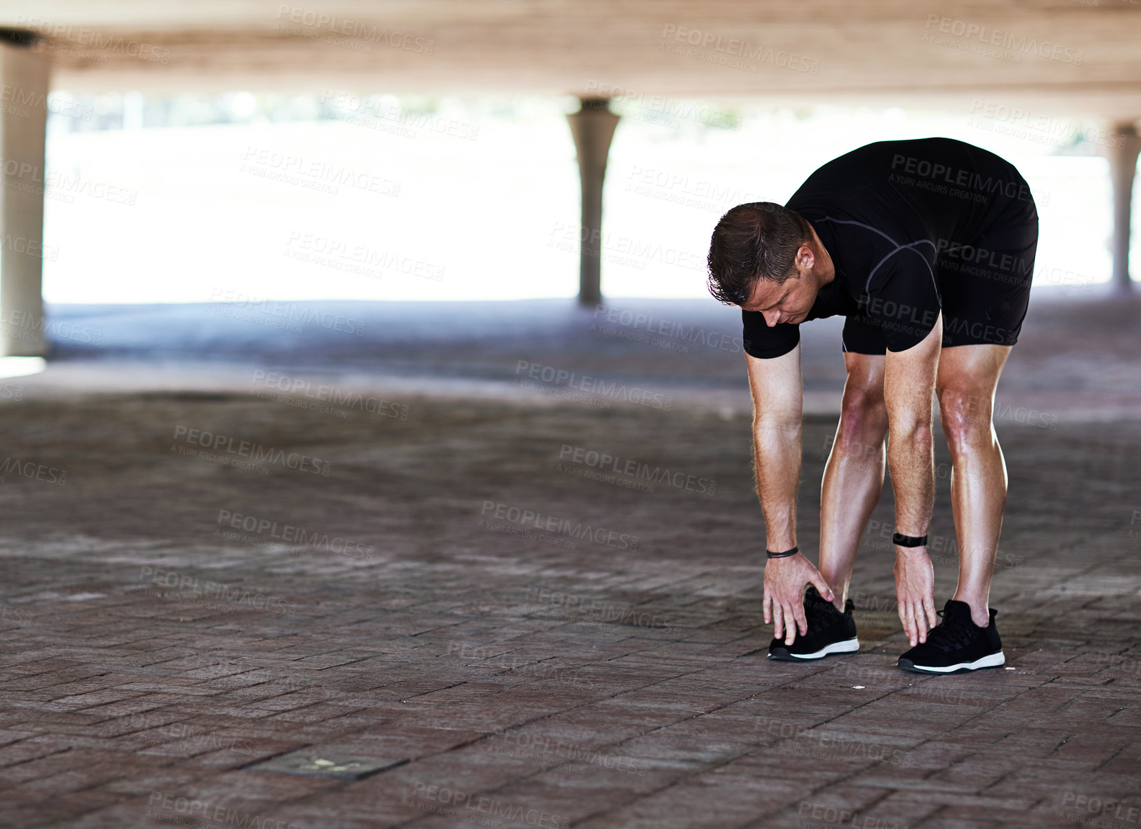 Buy stock photo Full length shot of a handsome young male athlete stretching during his workout in the city