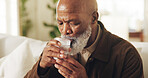 Drinking water, black man and hydration in home for wellness, detox and liquid in lounge. Mature person, glass and fluid for digestion, thirst and nutrition in house with electrolytes for retirement