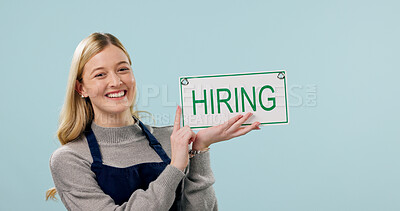 Buy stock photo Portrait, woman and hiring sign for cafe in studio, recruitment announcement and space. Happy barista, poster or board with onboarding information, job vacancy or work opportunity on blue background