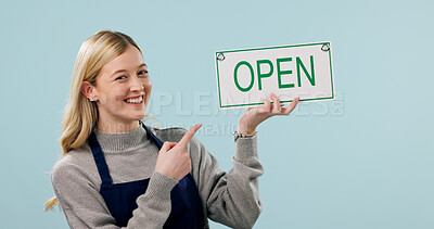 Buy stock photo Open, happy and portrait of woman as cafe owner in studio to welcome, announcement or signage. Smile, pointing and advertising for hospitality career, store or waitress with poster on blue background