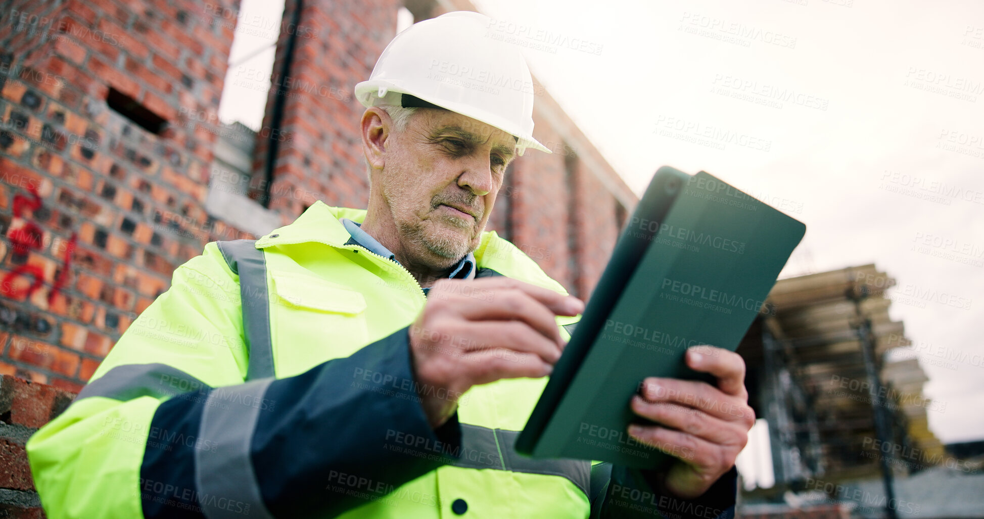 Buy stock photo Serious, civil engineer and man with tablet on construction site, online and planning for renovation. Architect, low angle and mature person with technology, research or info for property development