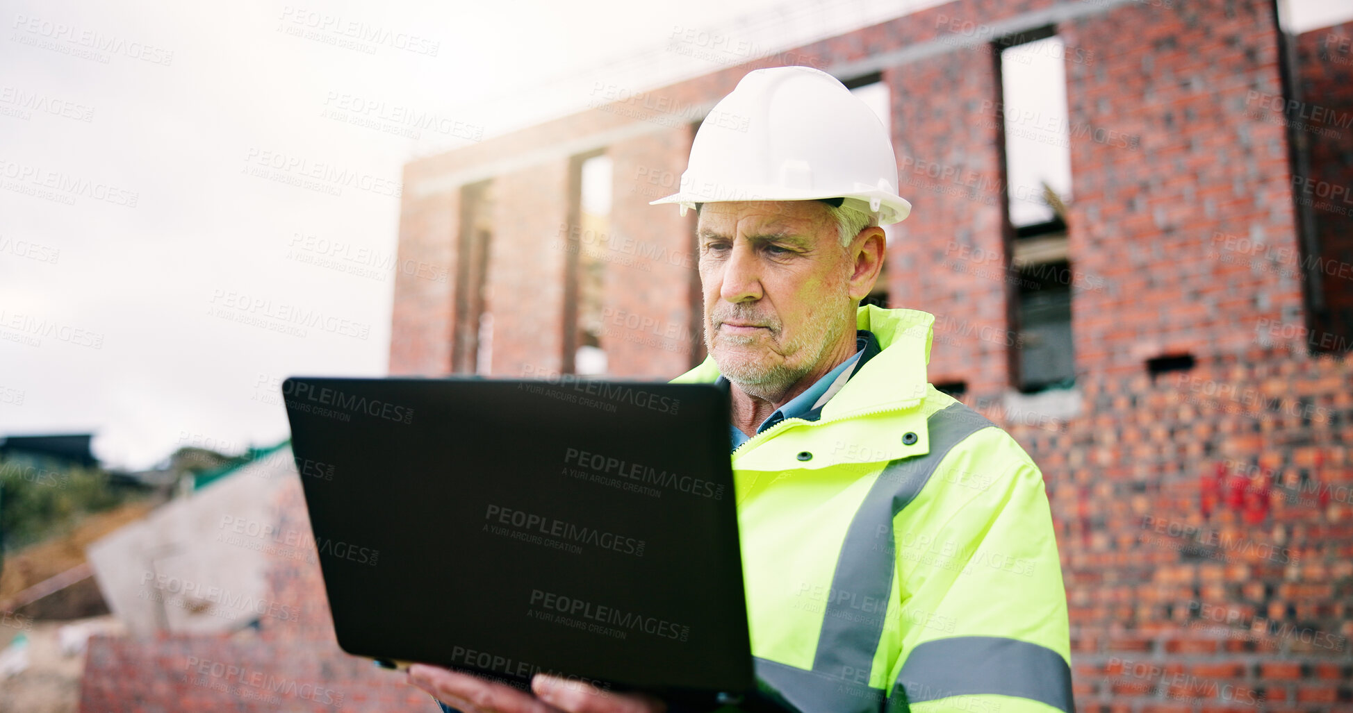 Buy stock photo Reading, man and construction worker on site with laptop for research on building renovation. Computer, plan and mature civil engineer with feedback on maintenance, repairs or property development.
