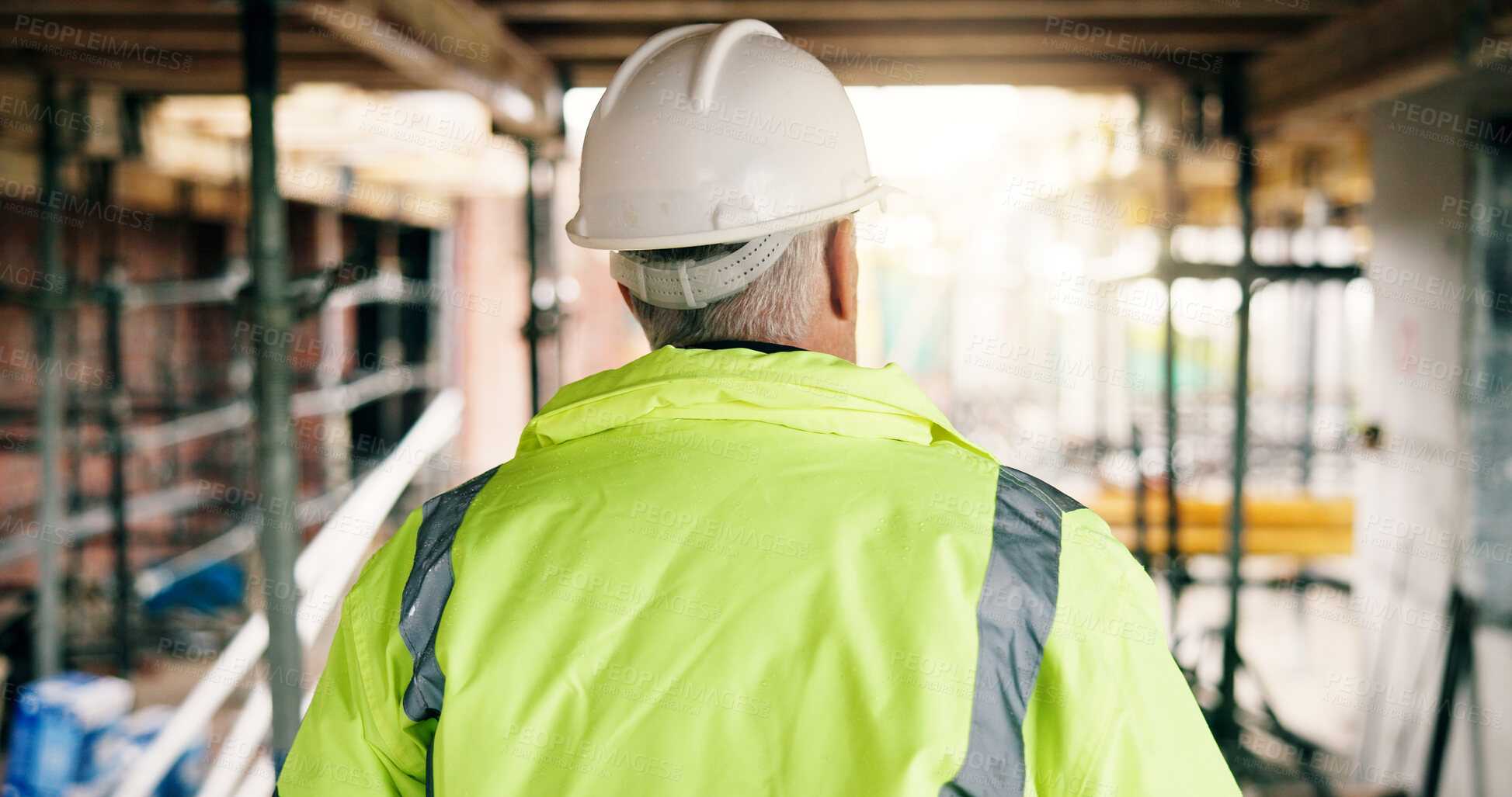 Buy stock photo Back, man and walk on construction site for renovation, scaffolding and building progress with service. Mature male person, engineering and remodeling project for infrastructure upgrade with helmet