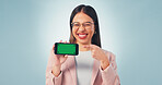 Happy, green screen and businesswoman with pointing at phone in studio for advertising finance app. Smile, portrait and financial advisor with cellphone for internet banking on blue background.
