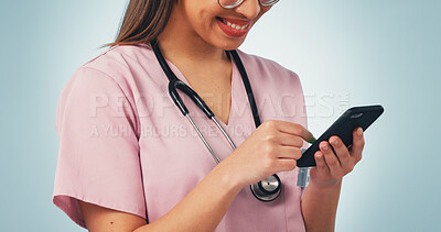 Buy stock photo Happy, woman and hands of nurse with phone in studio with telehealth, communication or texting on app. Smile, tech and healthcare worker scrolling on cellphone for medical research on blue background