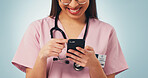Smile, woman and hands of nurse with phone in studio with telehealth, communication or texting on app. Happy, scrolling and healthcare worker with cellphone for medical research on blue background.
