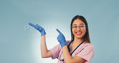 Buy stock photo Happy, portrait and nurse in studio pointing for health news, announcement and medical service. Mockup, space and woman with gesture for healthcare, wellness tips and clinic info on blue background