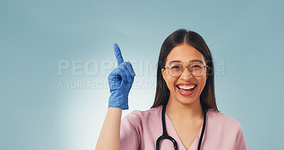 Buy stock photo Laugh, portrait and nurse in studio pointing for health news, announcement and medical service. Mockup, space and happy woman with gesture for healthcare, wellness tips and info on blue background