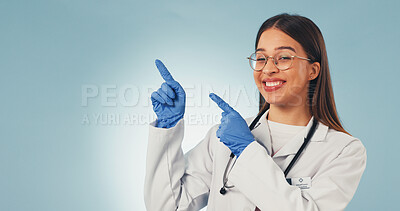 Buy stock photo Doctor, point and happy woman in studio, announcement and advice for healthcare services or portrait. Blue background, medical expert and person with smile, space and promotion with health options