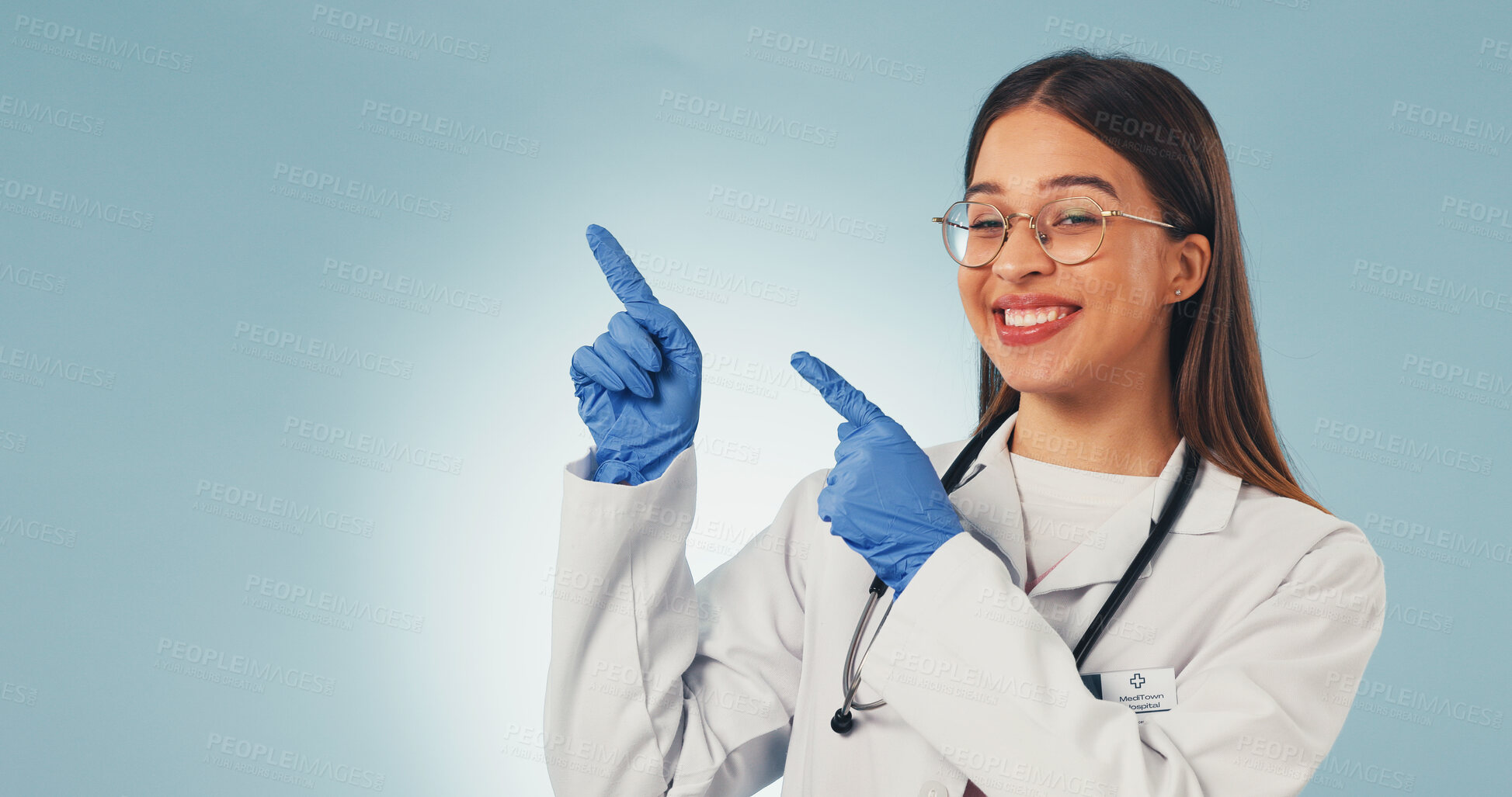 Buy stock photo Doctor, point and happy woman in studio, announcement and advice for healthcare services or portrait. Blue background, medical expert and person with smile, space and promotion with health options