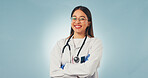Healthcare, doctor and happy woman in studio with arms crossed, portrait and space on blue background. Smile, confidence and medical worker with career integrity, about us and pride for wellness