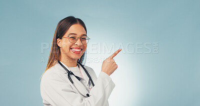 Buy stock photo Doctor, portrait and happy woman in studio, point and recommendation for healthcare service or space. Blue background, medical expert and person with smile, presentation and advice for health options