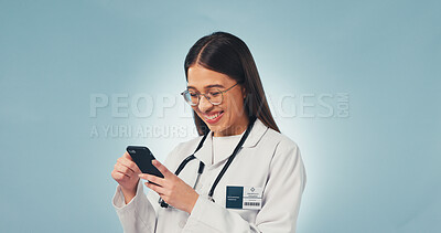 Buy stock photo Happy, woman and doctor with phone in studio with telehealth, consultation or texting on mobile app. Smile, tech and healthcare worker with cellphone for medical research on blue background by space.