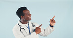 Doctor, decision and happy man in studio, point and recommendation for healthcare service and space. Blue background, medical expert and black person with smile, offer and advice for health options