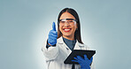 Portrait, scientist and thumbs up in studio with tablet, achievement or success for medical innovation. Space, happy woman and like sign with tech, science research approval or PPE on blue background