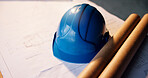 Helmet, construction and blueprint with safety gear on site for building development or security. Hard hat, documents or floor layout for architecture, project planning or design structure on desk