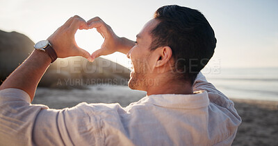 Buy stock photo Smile, man and heart at beach for travel, love symbol and celebration for summer holiday. Happy, male person and hand gesture at seashore for kindness, romance icon and adventure for vacation getaway