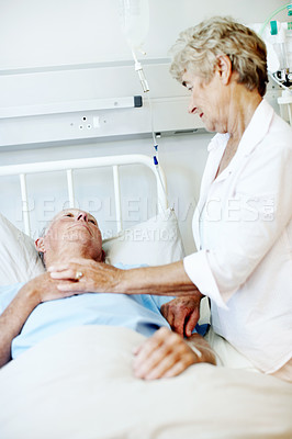 Buy stock photo Concern, visit and old couple in hospital bed for support, comfort and hope for surgery recovery. Love, healthcare and senior man and woman holding hands for compassion, affection or care for healing