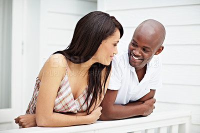 Buy stock photo Shot of a young couple leaning on the railing of their balcony