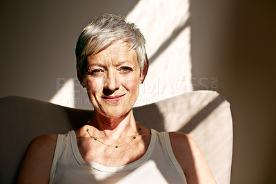 Buy stock photo Portrait of a mature woman sitting in a chair bathed in sunlight