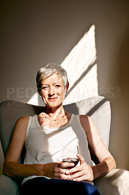 Buy stock photo Portrait of a mature woman drinking wine while sitting in a chair bathed in sunlight