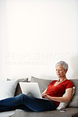 Buy stock photo Shot of a mature woman sitting in her living room using a laptop