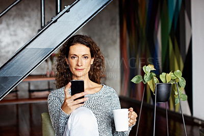 Buy stock photo Portrait of a mature woman using her cellphone while sitting on a chair in her living room