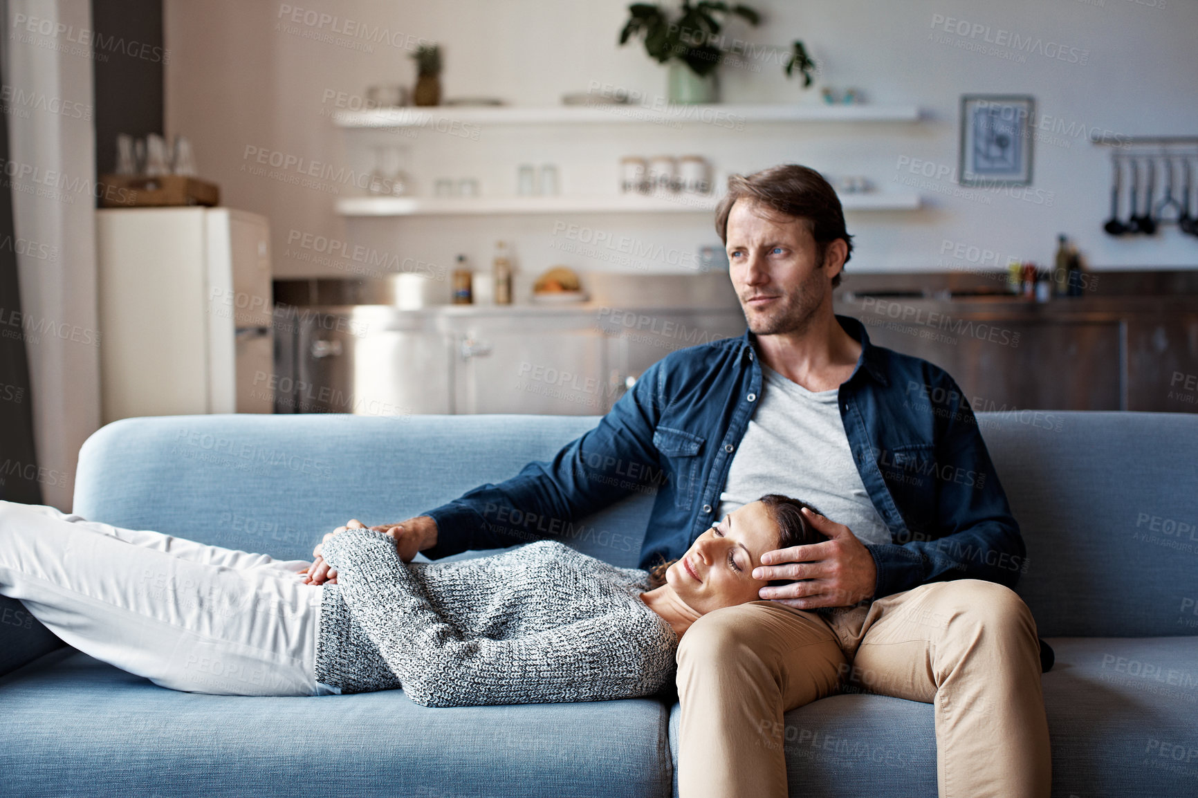 Buy stock photo Shot of a mature woman lying with her head on her husband's lap on the sofa