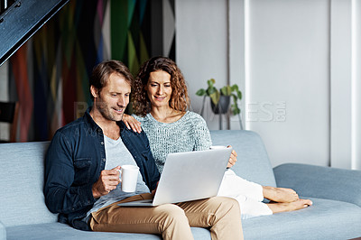 Buy stock photo Shot of a mature couple sitting on their sofa using a laptop