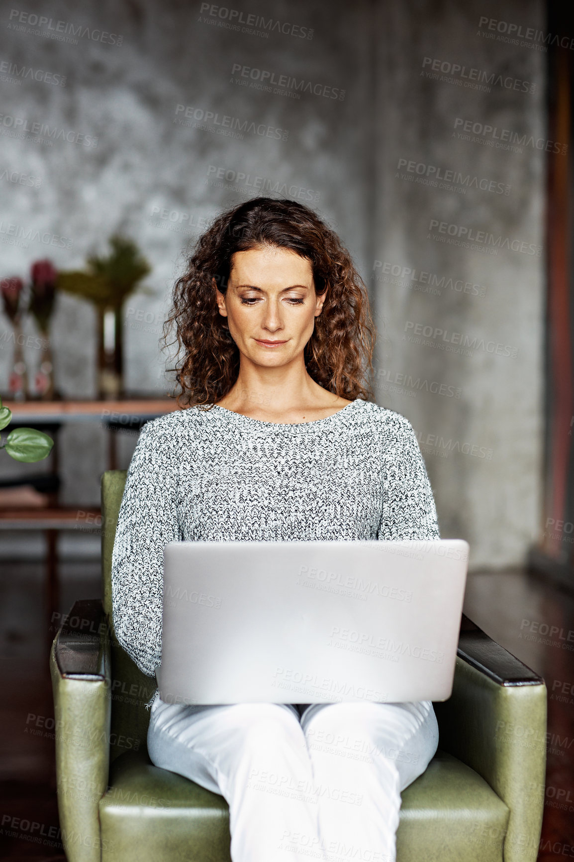 Buy stock photo Shot of a mature woman sitting on a chair in her living room using a laptop