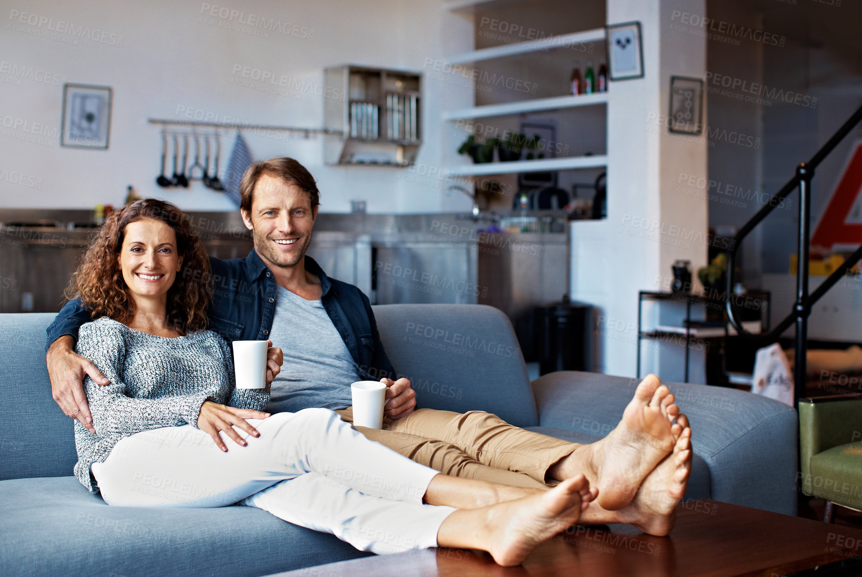 Buy stock photo Portrait of a content mature couple sitting on their living room sofa drinking coffee