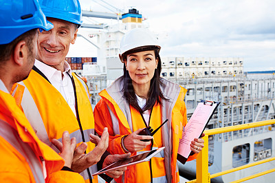 Buy stock photo Shot of workers talking over a digital tablet while standing on a large commercial dock