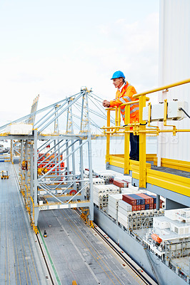Buy stock photo Shot of a man in workwear standing on a walkway looking  out over at a large commercial dock