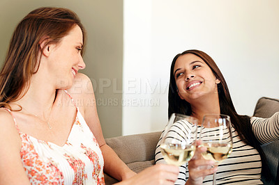 Buy stock photo Shot of two friends talking together and drinking wine while sitting on the sofa at home